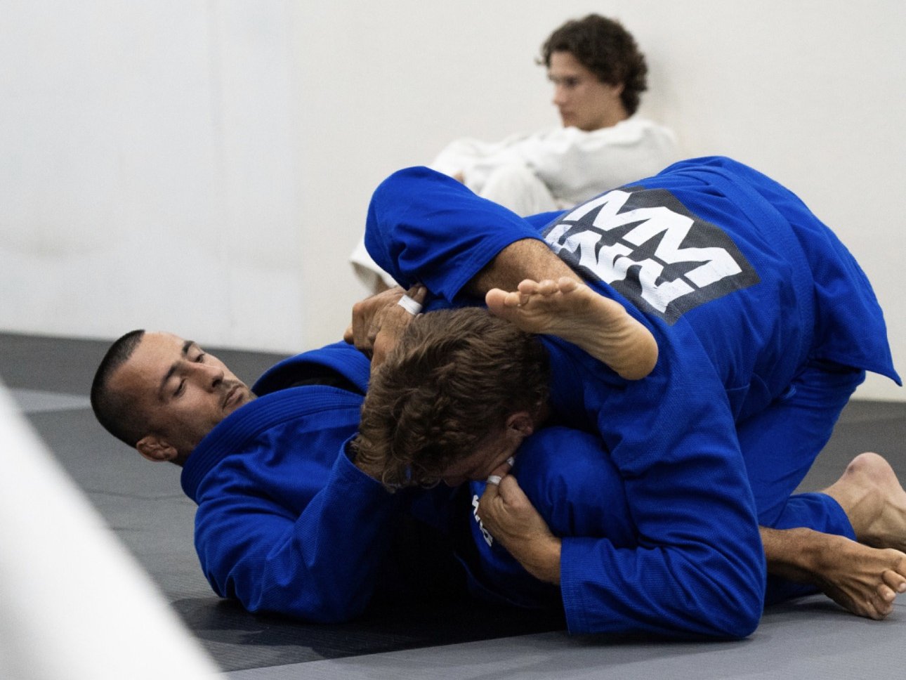 Two members rolling in blue gis during a Gi class