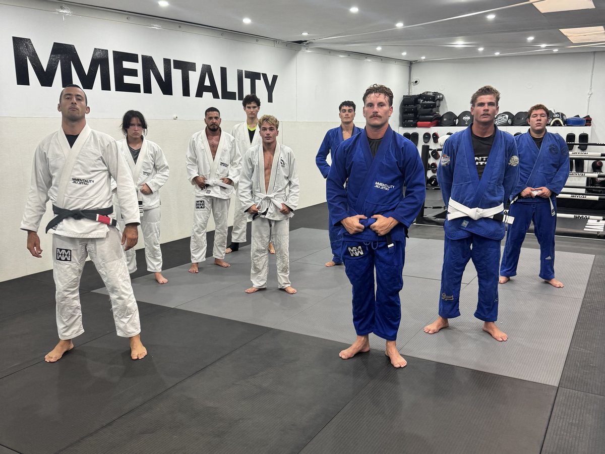A Gi class lined up on the mats in front of the Mentality wall