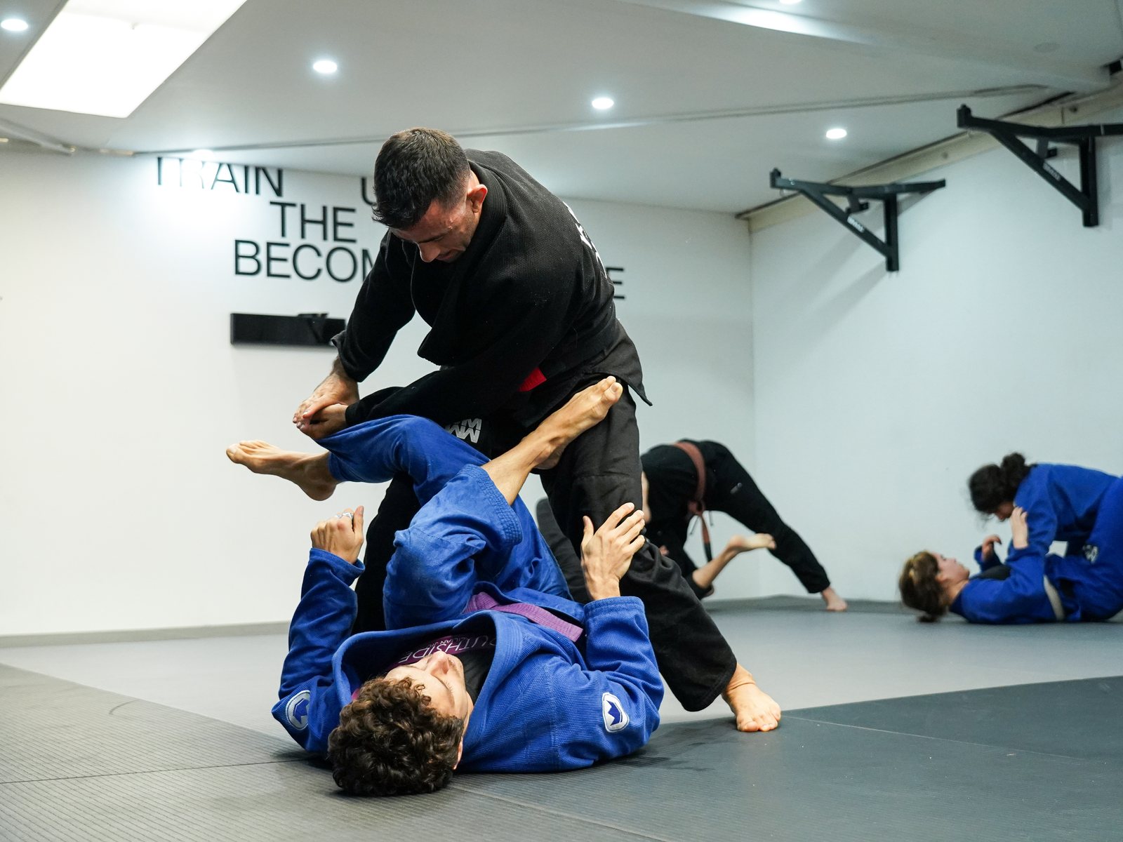 A black belt coach passing the guard of a purple belt during Gi training at Mentality Jiu Jitsu