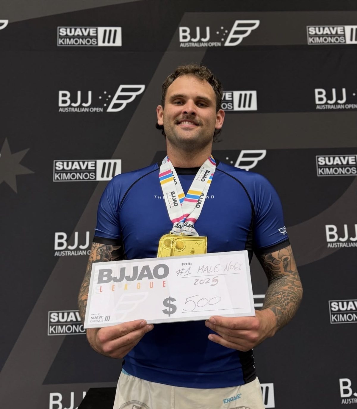 Mentality Jiu Jitsu member holding the BJJAO League #1 Male No-Gi 2025 cheque with a gold medal