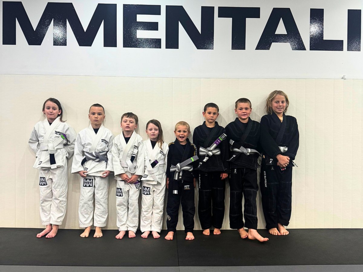 Kids Jiu Jitsu students lined up in their gis in front of the Mentality wall