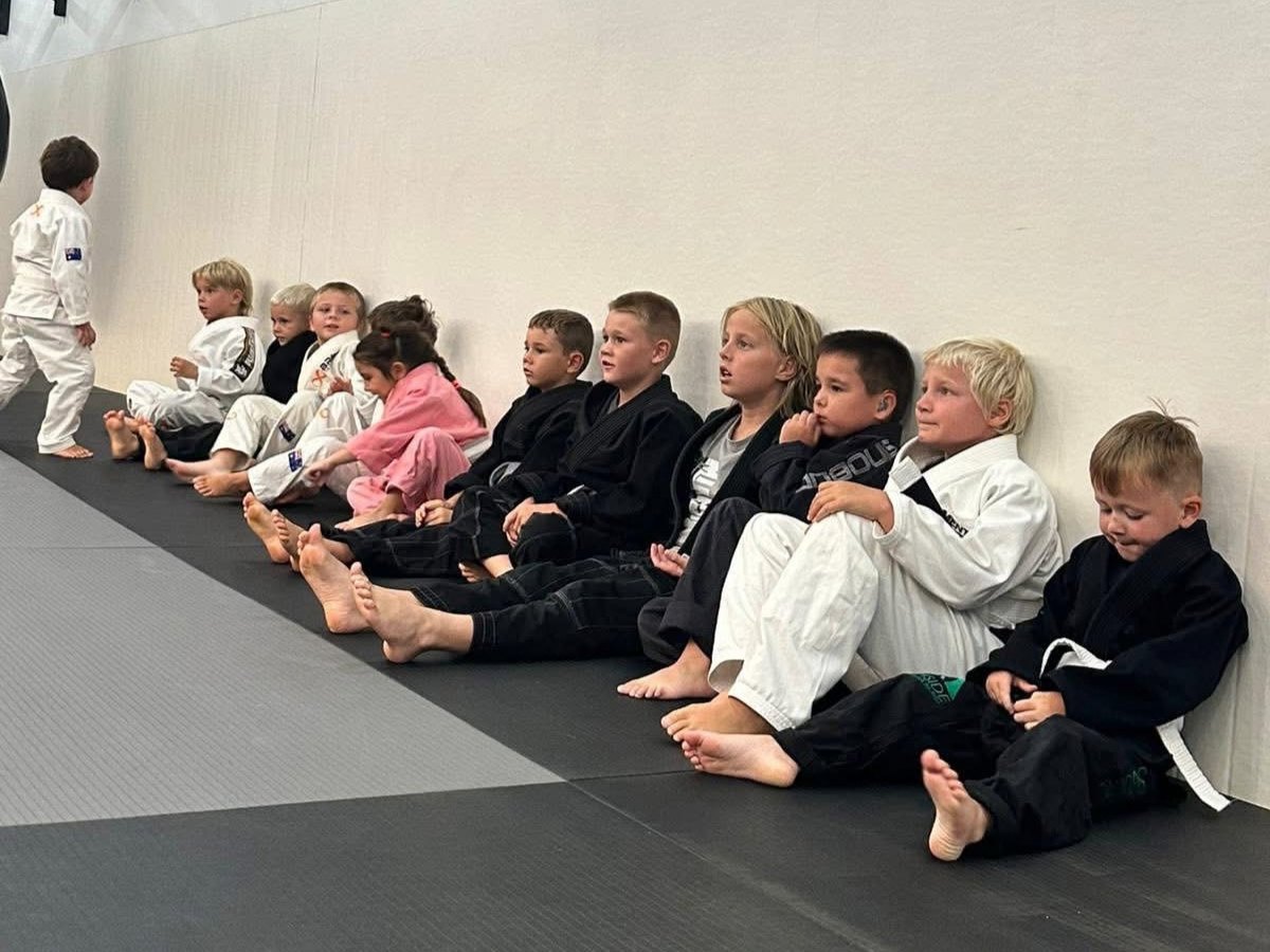 Kids sitting along the wall watching a technique demonstration