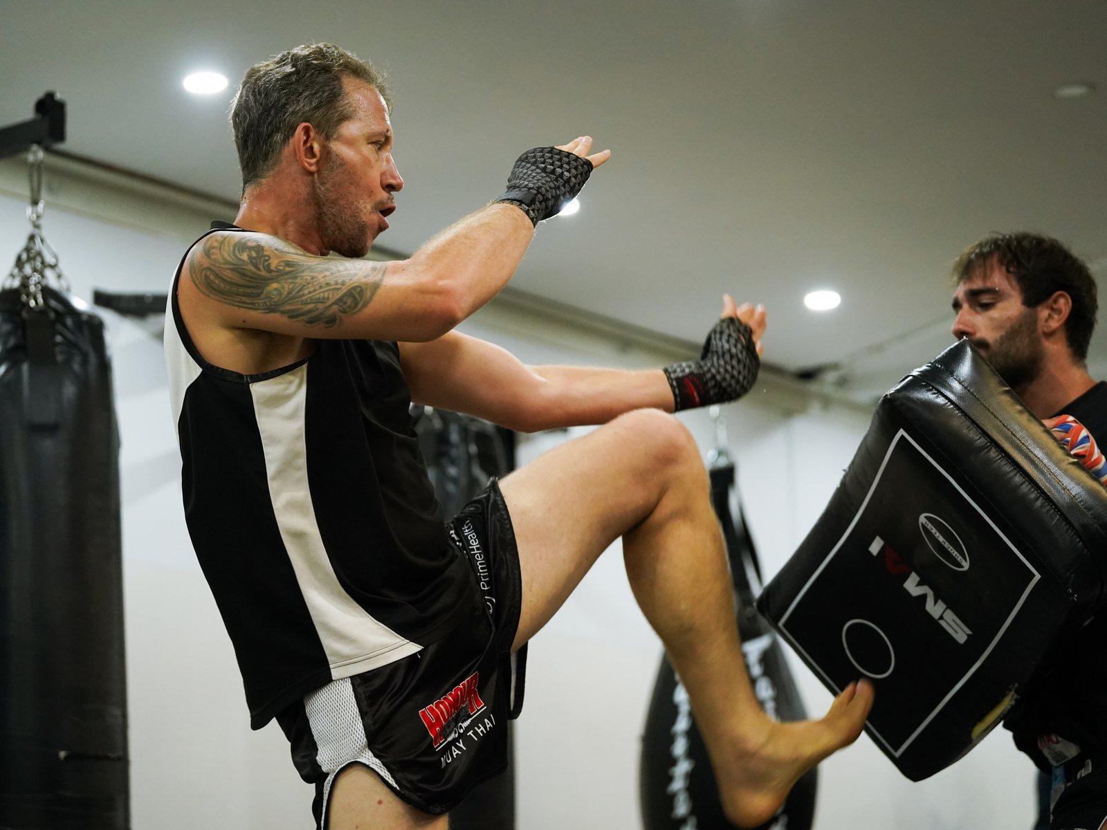 A member driving a knee into a kick shield during Muay Thai pad work at Mentality Jiu Jitsu