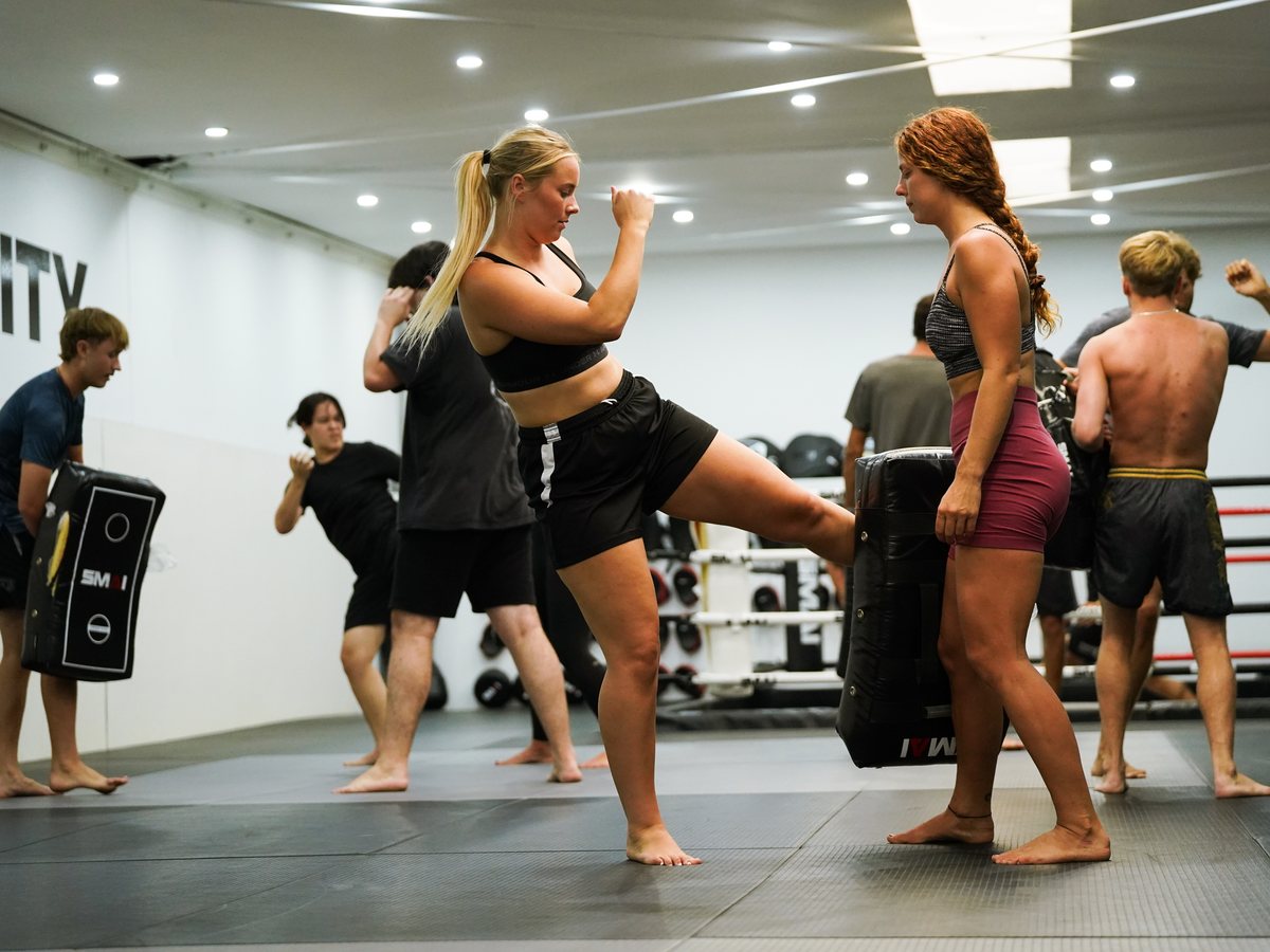 A member throwing a push kick into a kick shield held by her partner