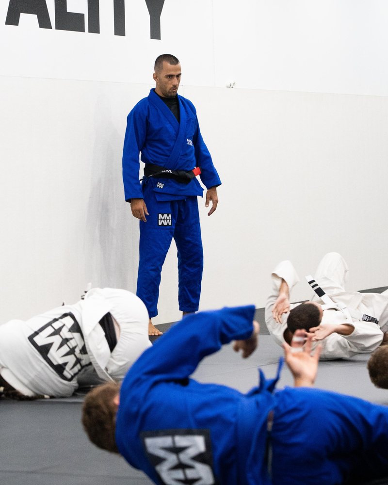 A black belt coach watching members run warm-up drills