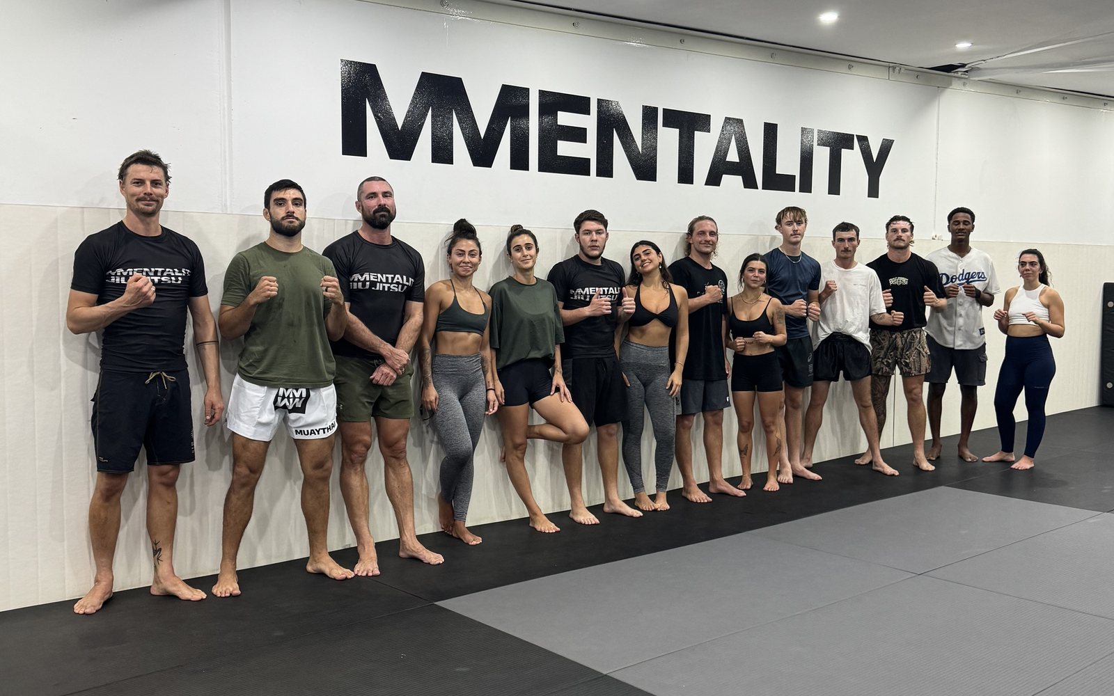 Mentality Jiu Jitsu and Muay Thai members lined up in front of the Mentality wall